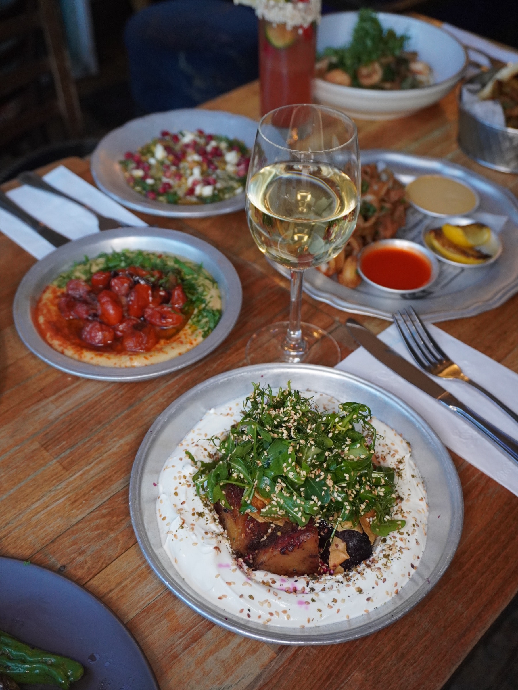 A table at 19 Cleveland set with shared plates and a glass of white wine