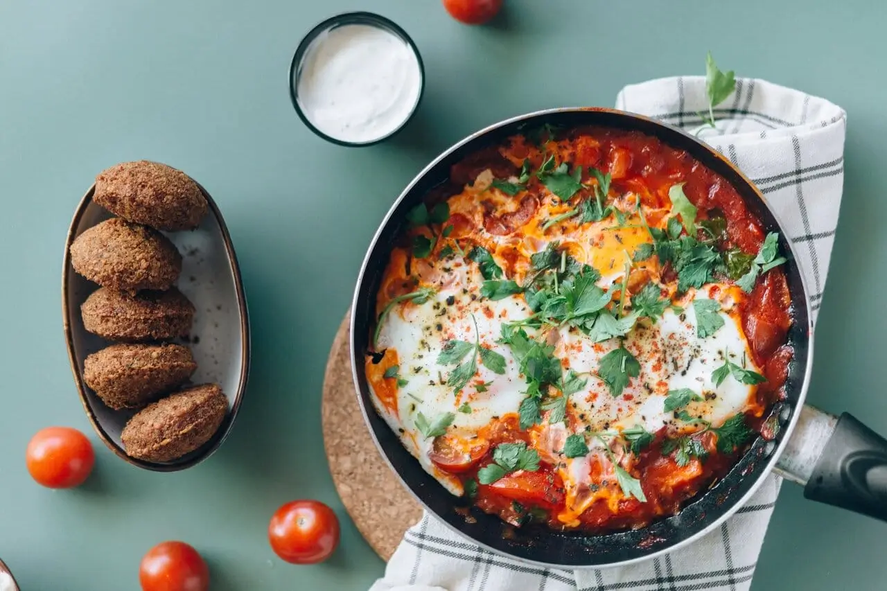 a close up of a pan of food with tomatoes and bread