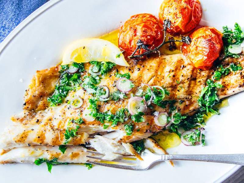 there is a plate of fish with vegetables and a fork