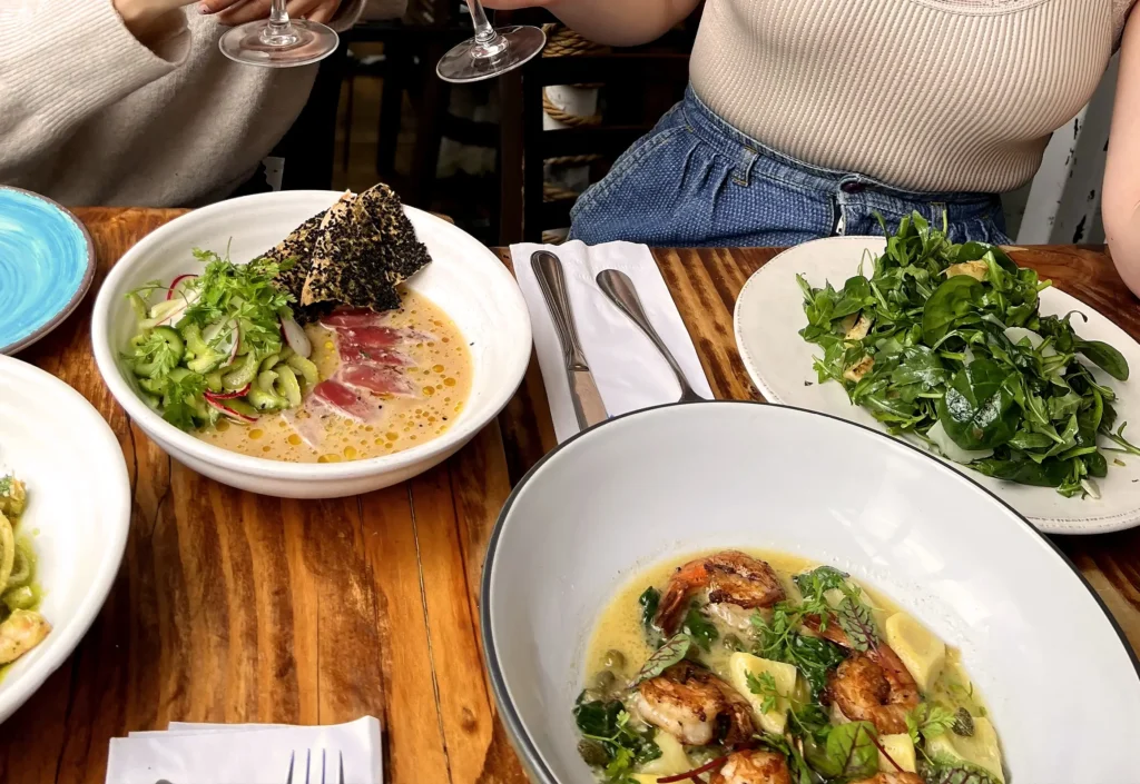 several plates of food are on a table with a glass of wine