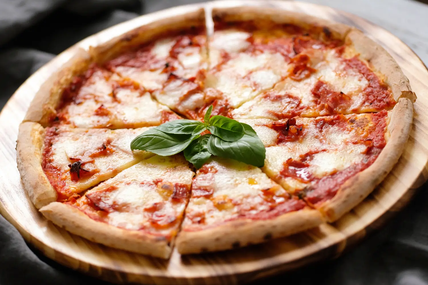 there is a pizza with cheese and basil on a wooden plate