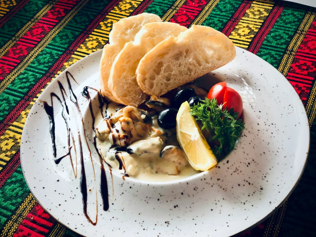 there is a plate of food with bread, olives, and a salad