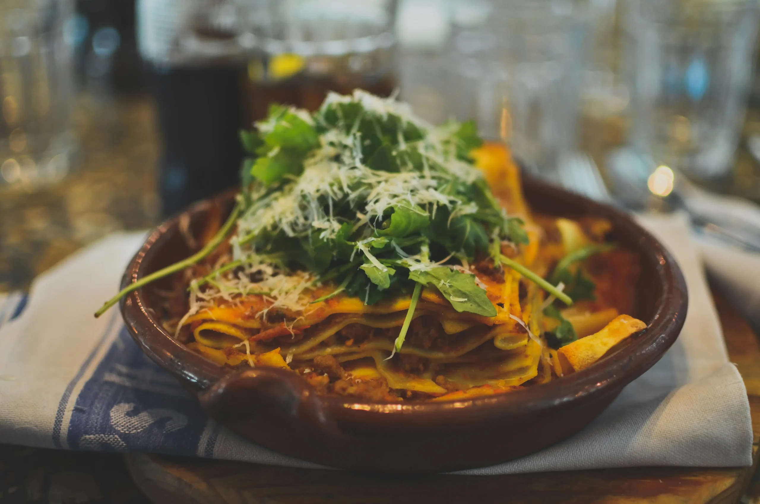 there is a bowl of pasta with cheese and greens on top