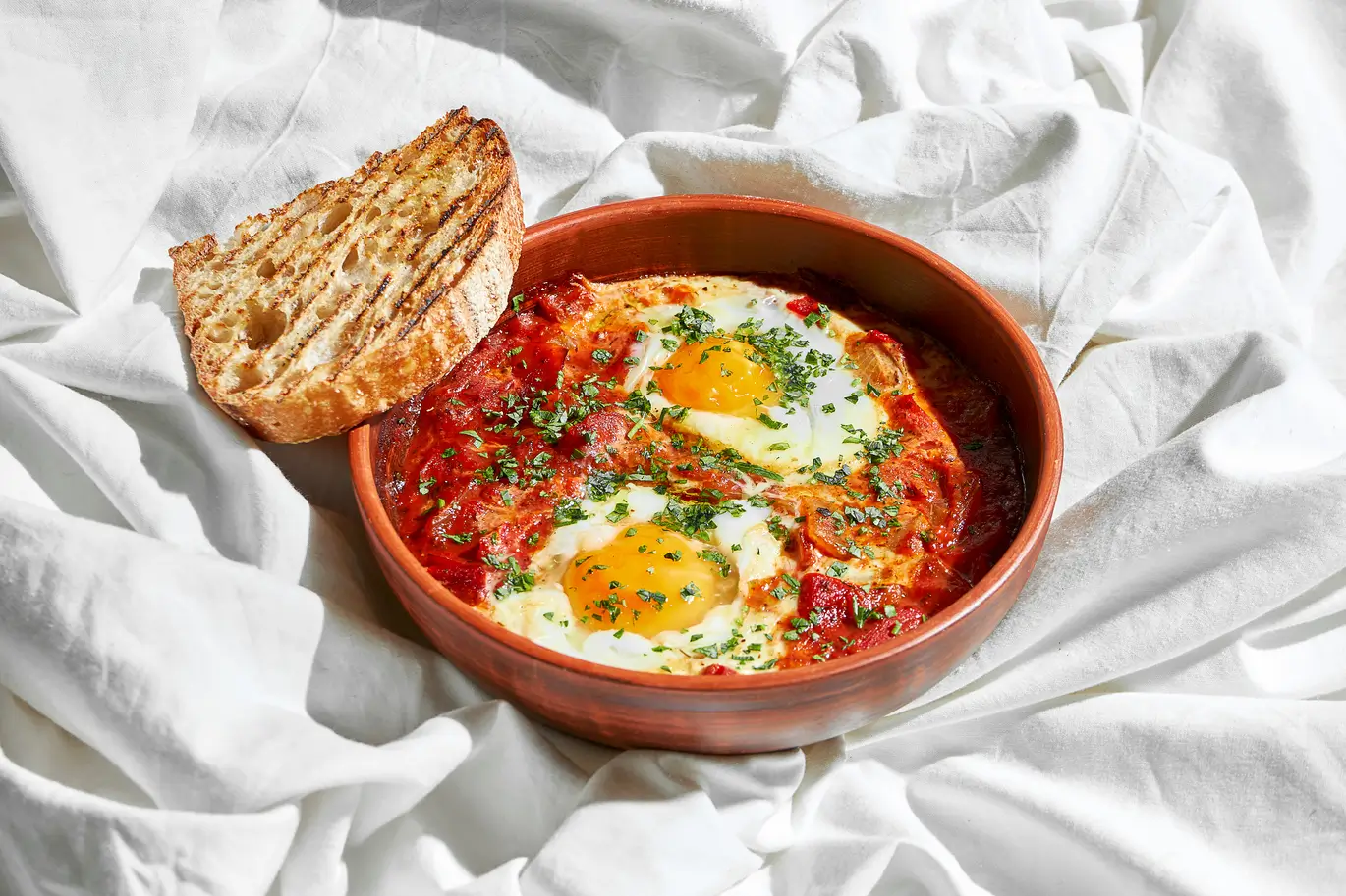 there is a bowl of food with bread and eggs on a bed