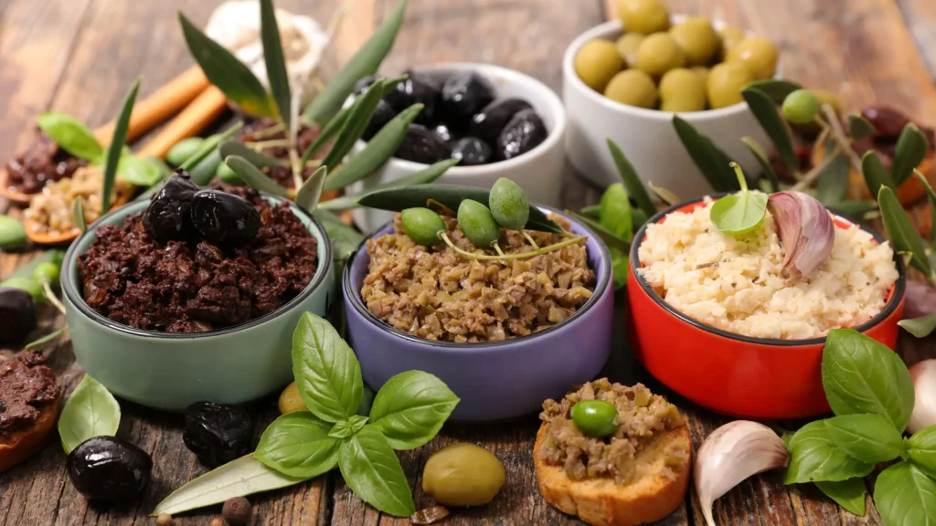 a close up of a table with bowls of food and olives