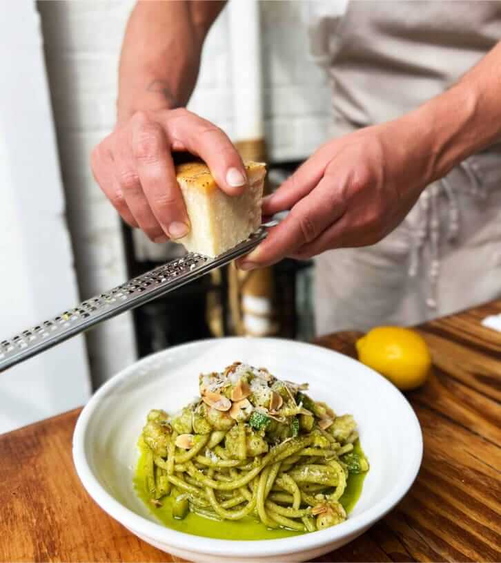 someone is grating some bread into a bowl of pasta