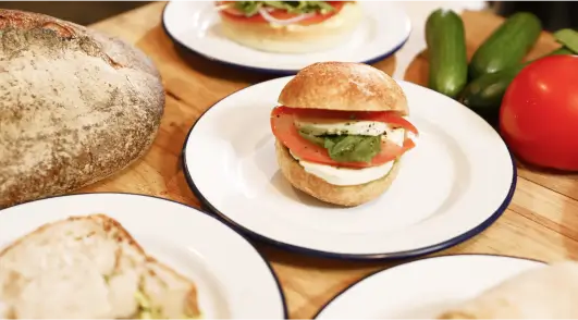 there are four plates of sandwiches on a table with bread