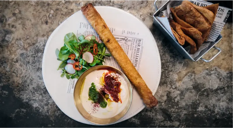 there is a plate of food with a roll and a bowl of dip