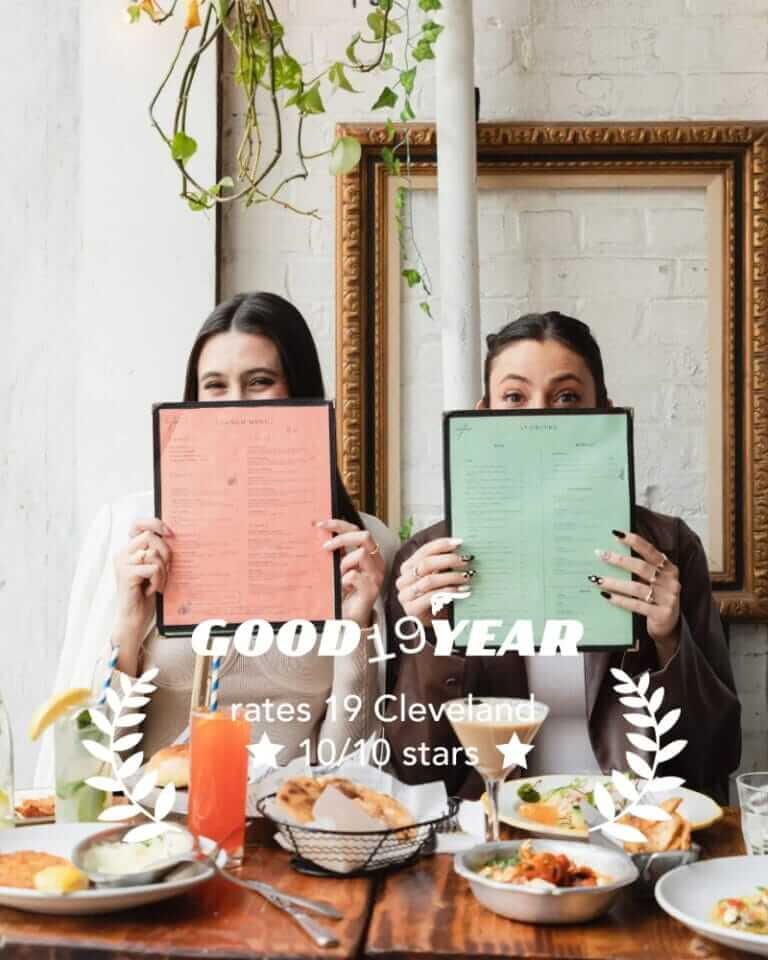 two women holding up a menu and a menu card at a table