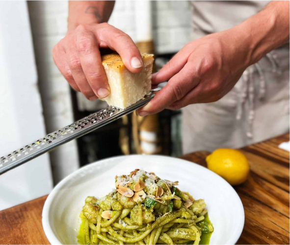 someone is grating a piece of bread over a bowl of pasta