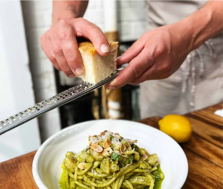 someone is preparing a dish of pasta with pesto sauce