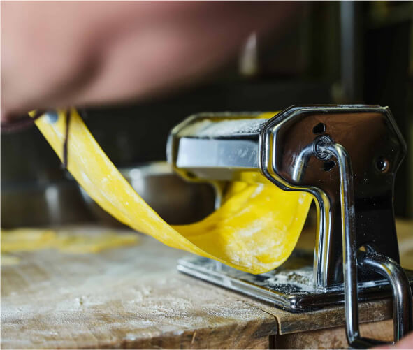 someone is peeling a pasta with a metal cutter on a wooden table