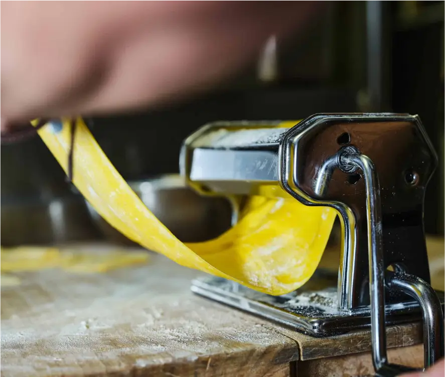 someone is peeling a pasta with a machine on a wooden table