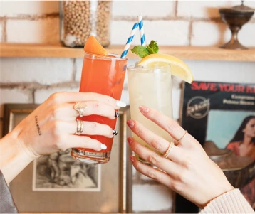 someone holding a glass of juice and a drink with a straw