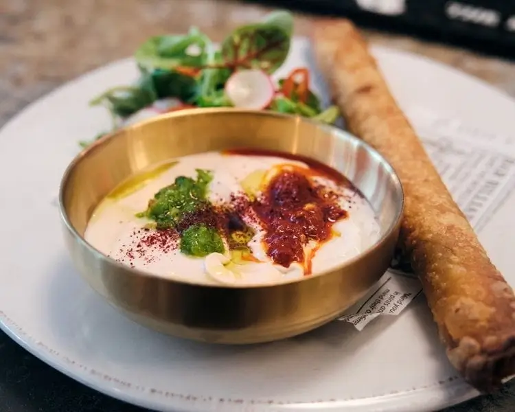 there is a plate with a bowl of soup and a roll on it