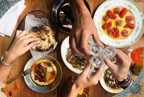 people are enjoying a meal together at a table with plates of food