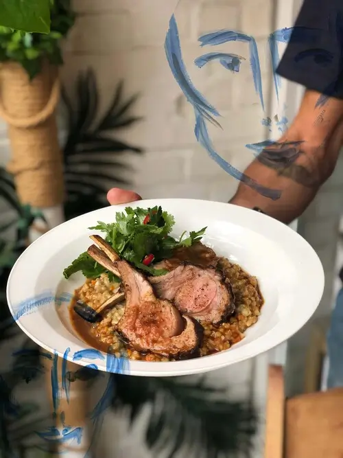 someone holding a plate of food with meat and vegetables on it