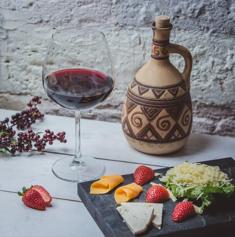 there is a bottle of wine and a plate of cheese and strawberries