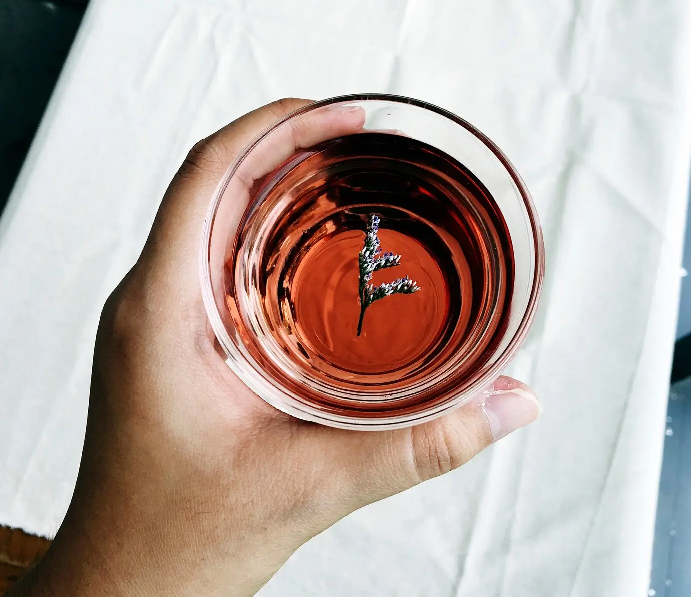 someone holding a glass of red liquid with a clock on it