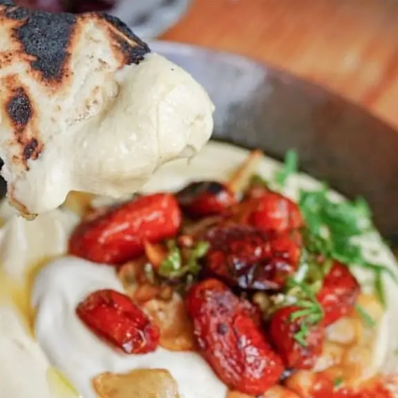 a close up of a piece of bread being held over a bowl of food