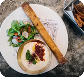 there is a plate of food with a roll and a bowl of dip