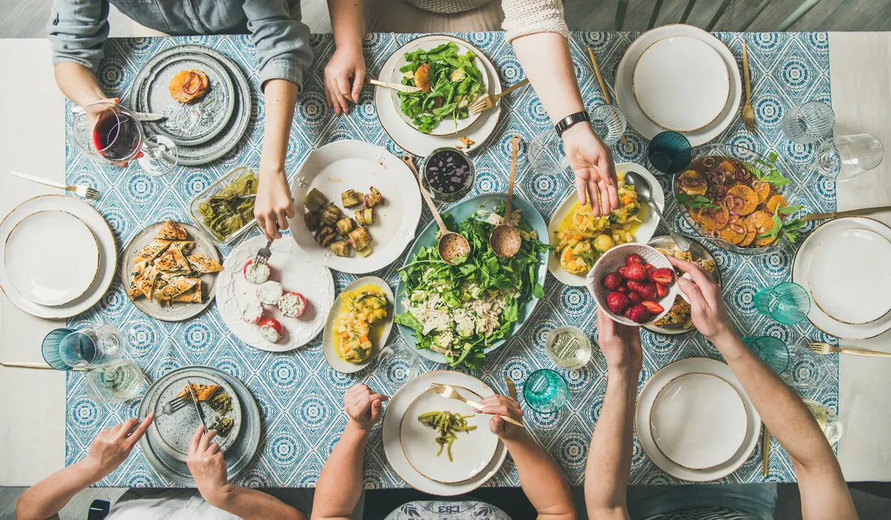 people sitting at a table with plates of food and glasses of wine