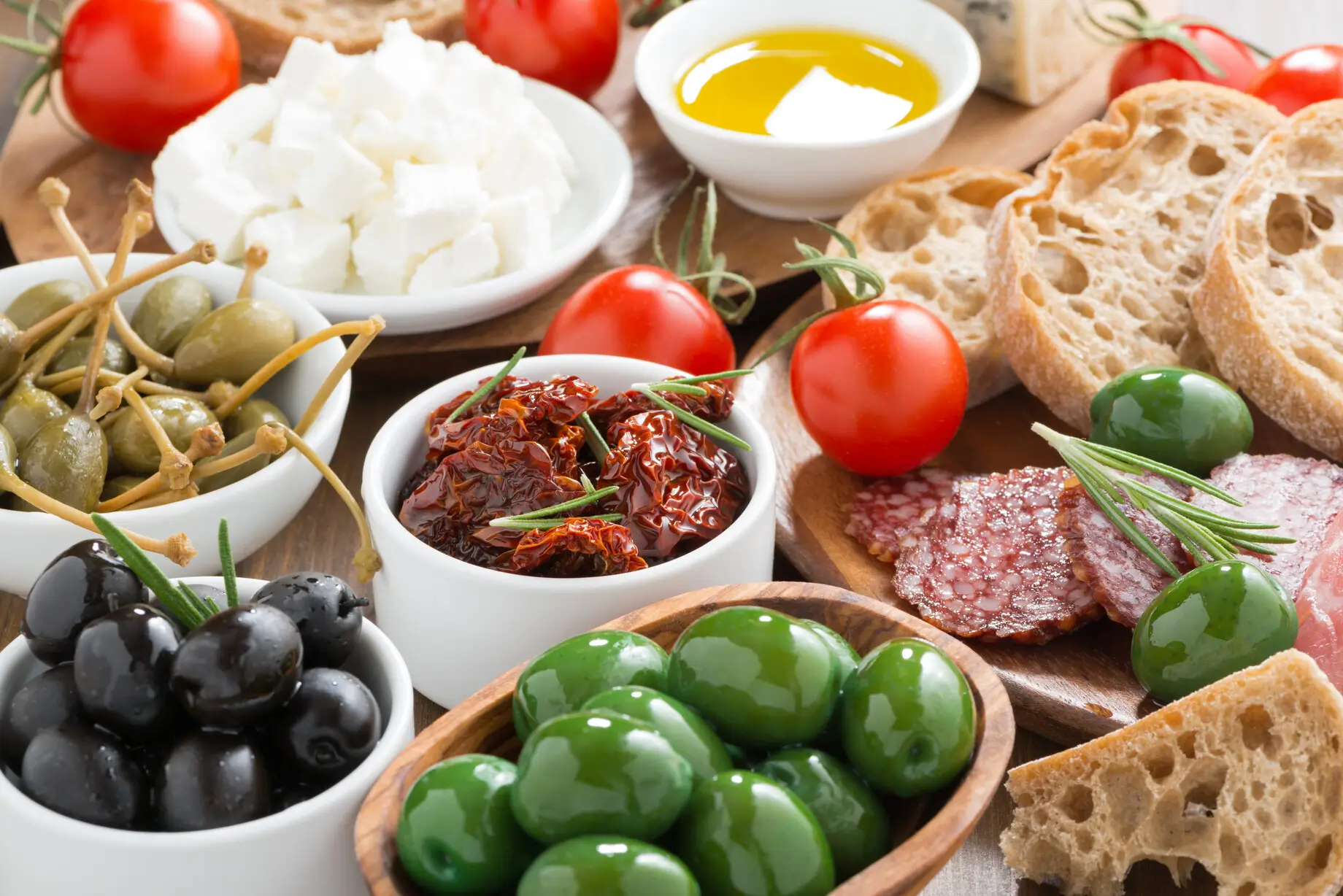 there are many different types of olives and bread on the table