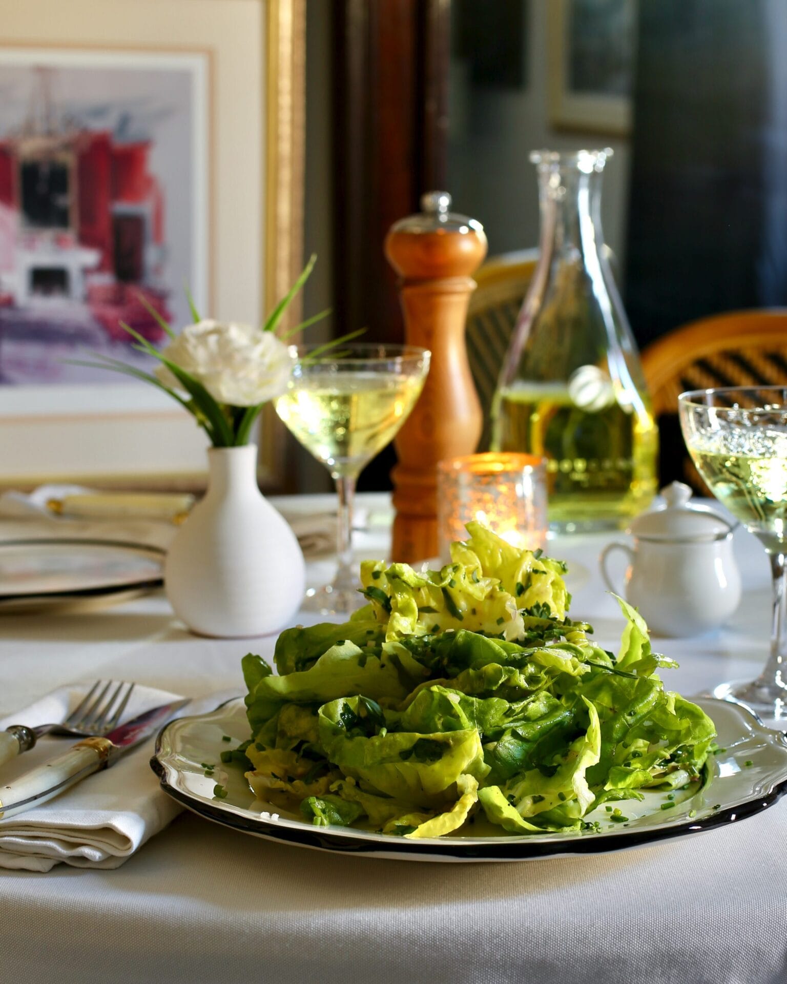 there is a plate of salad on a table with a glass of wine
