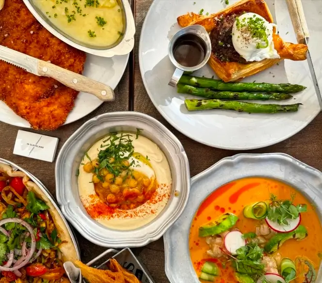 several plates of food are arranged on a table with utensils