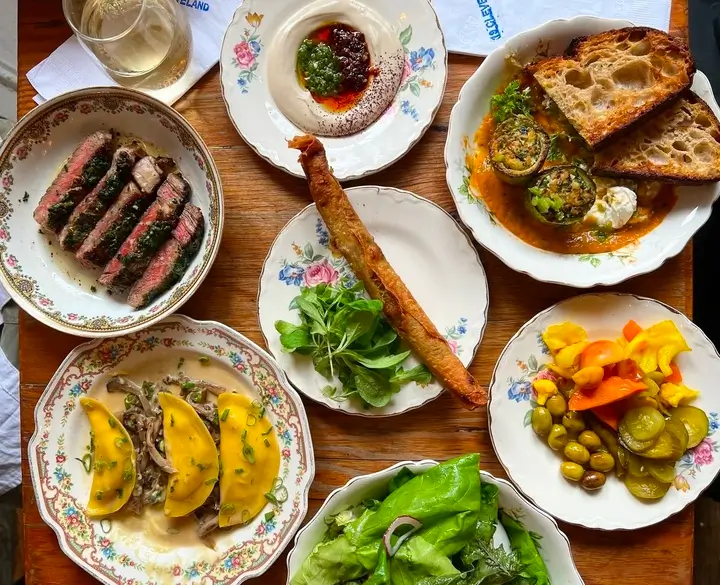 a close up of a table with plates of food and a glass of wine
