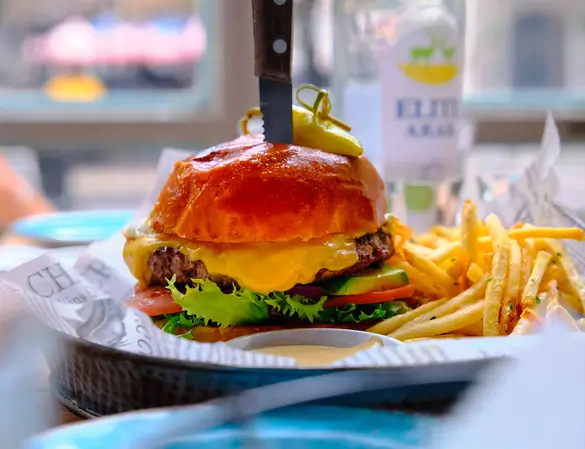 there is a hamburger with cheese and pickles on it and fries