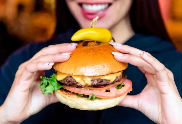 arafed woman holding a hamburger with a pickle on top