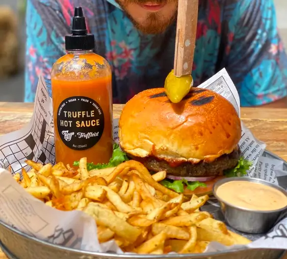 araffle hot sauce on a burger and fries with a man in the background