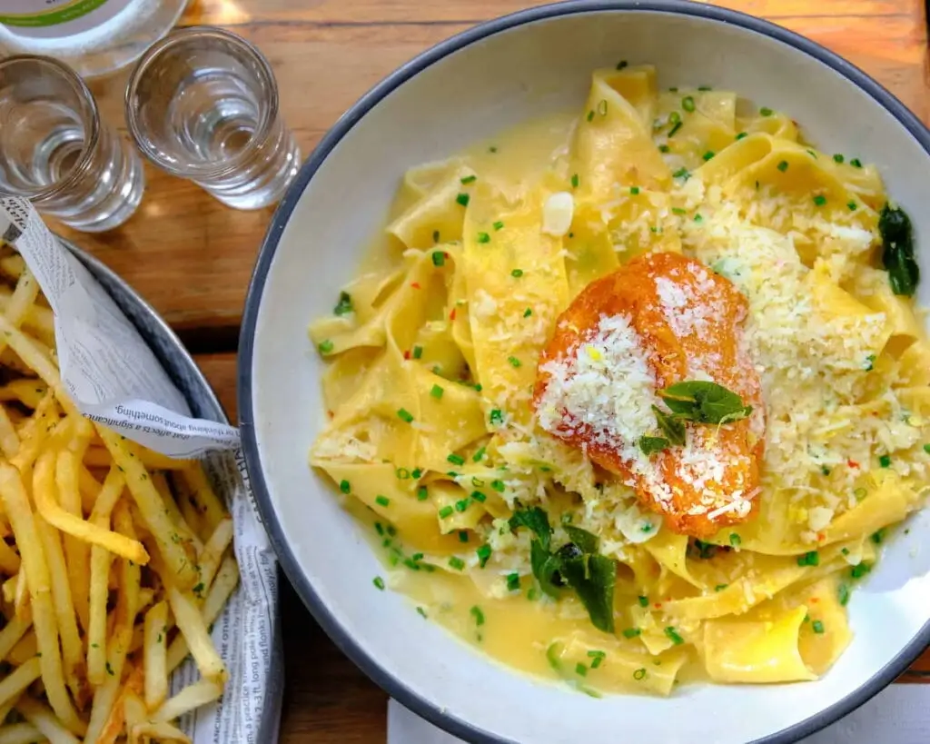there is a bowl of pasta with a piece of salmon on top of it