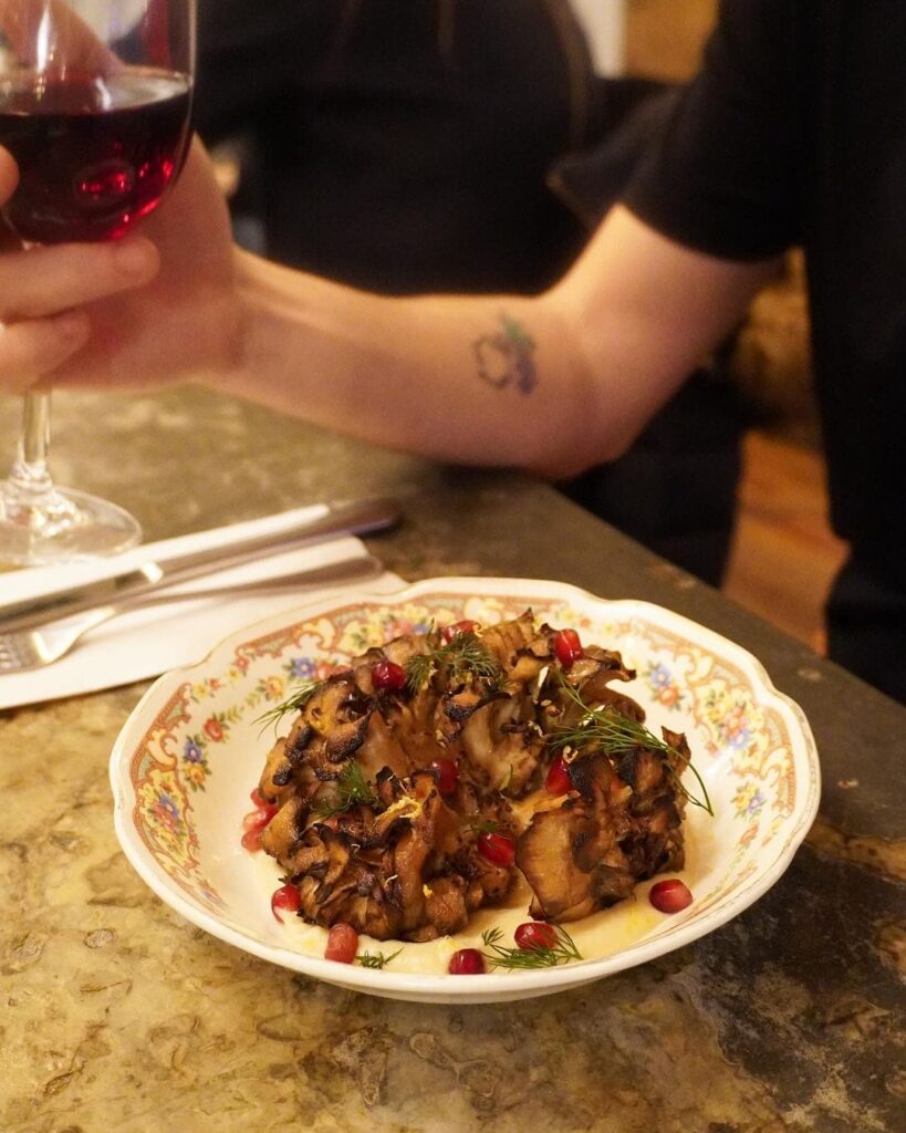 someone is holding a glass of wine and a plate of food