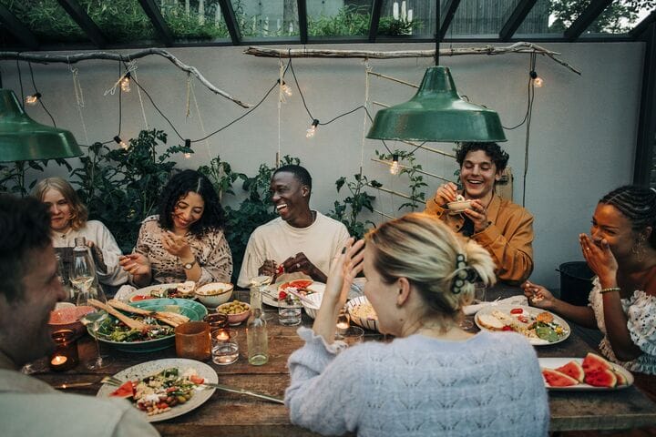 several people sitting around a table eating food and drinking