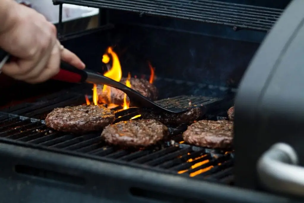 someone is cooking hamburgers on a grill with a spatula