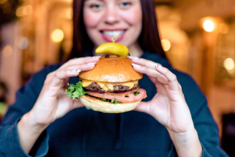 arafed woman holding a hamburger with pickles and a pickle