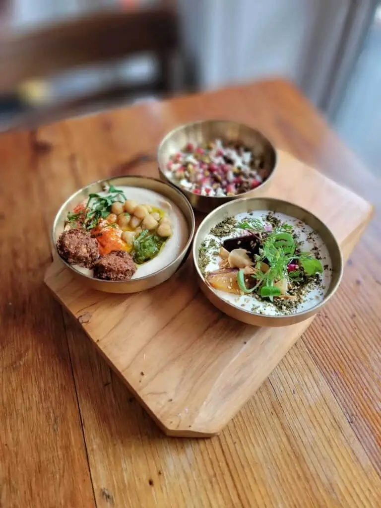 three bowls of food are sitting on a wooden tray