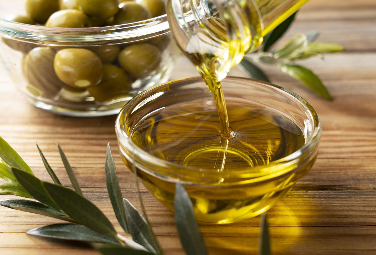 olives being poured into a bowl with olive oil