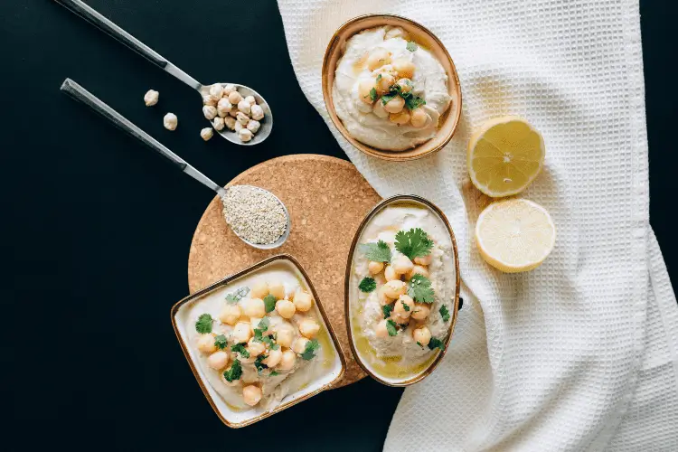 two bowls of food with rice, lemon and chicklings on a table