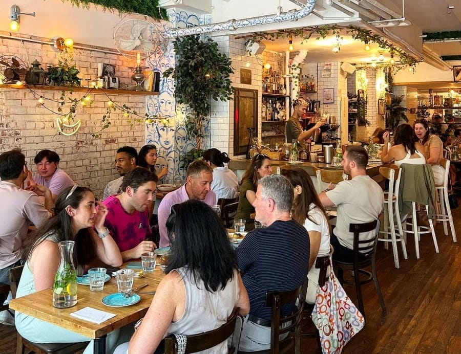 people sitting at tables in a restaurant eating and drinking