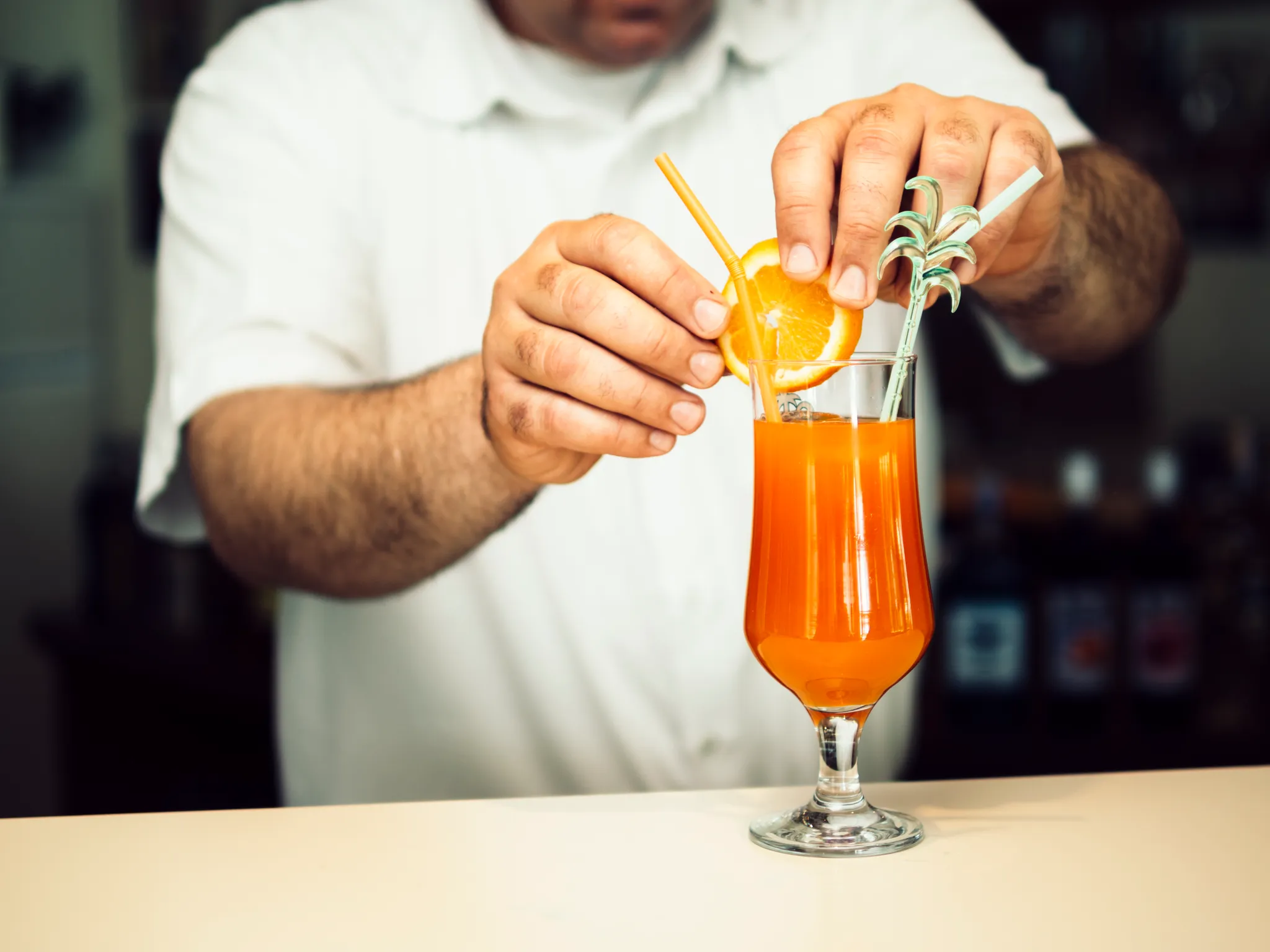 Bartender zesting orange over cocktail
