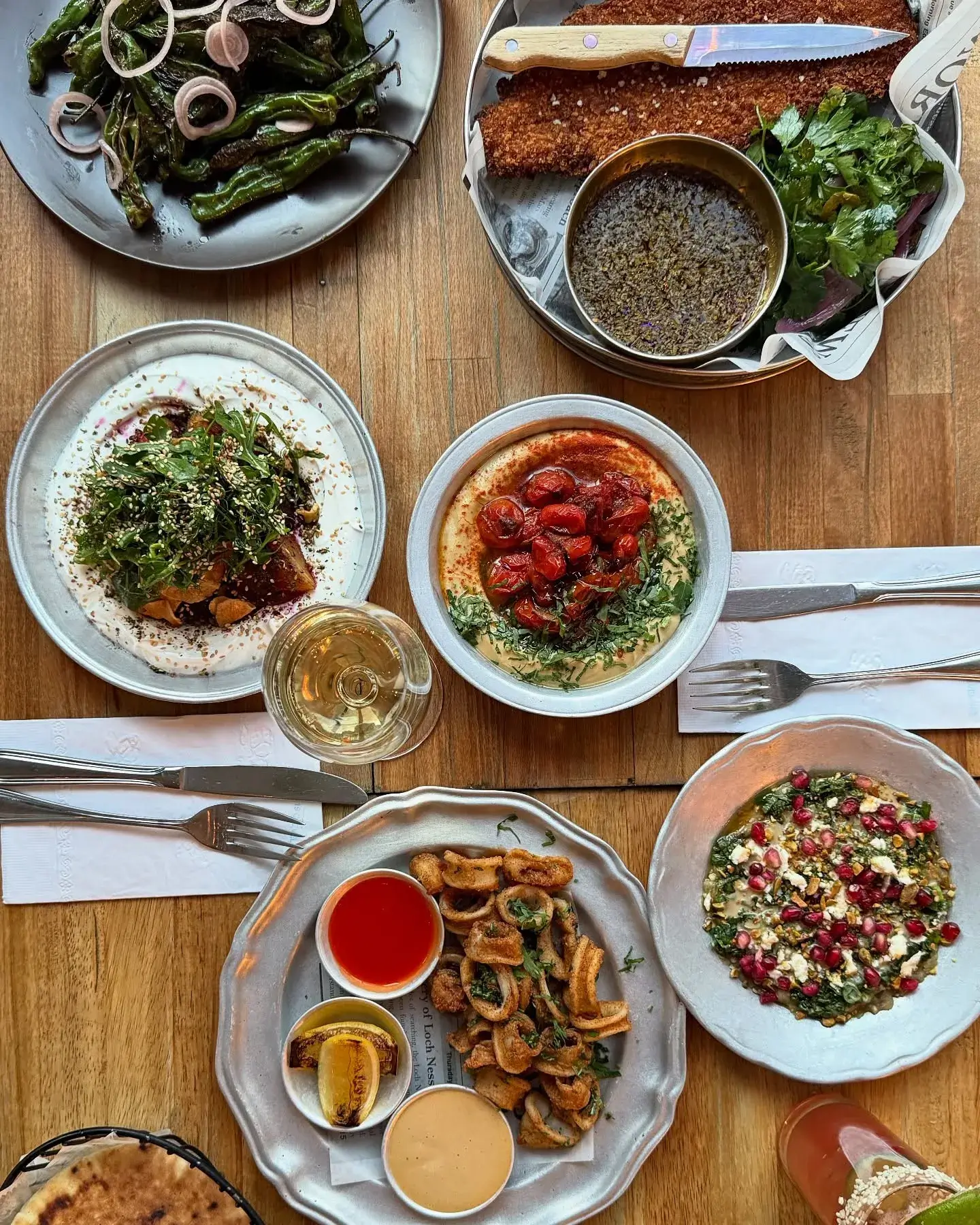 A table with plates of salad, grilled beetroot, smoked eggplant, and hummus