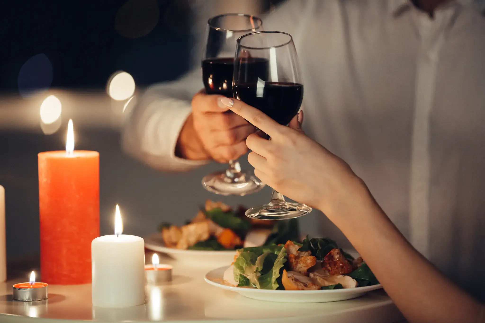 People enjoying a meal together at a candlelit table with shared plates.